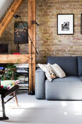 Un salon chaleureux avec canapé gris et un mur de brique 