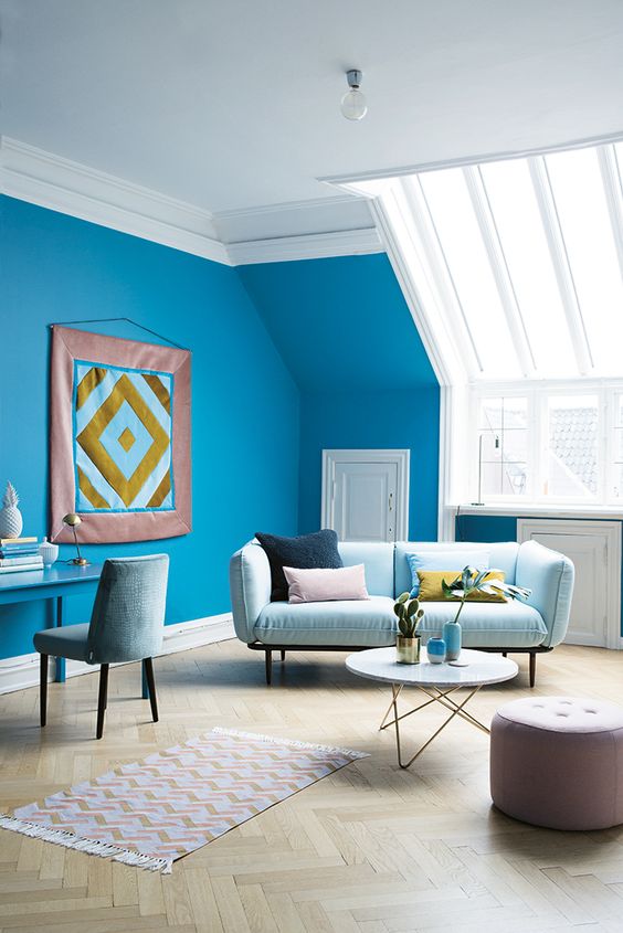 Un salon lumineux et spacieux avec un mur bleu cyan et une décoration scandinave