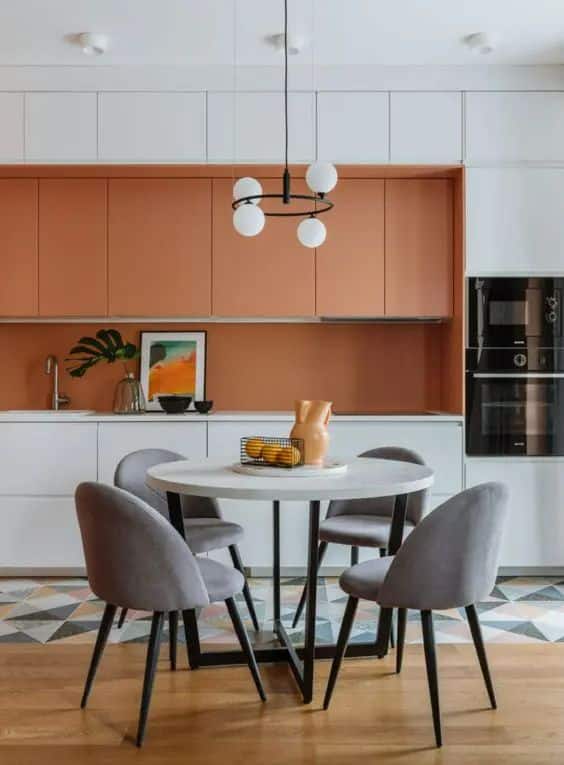 Cuisine design blanche et orange avec coin repas