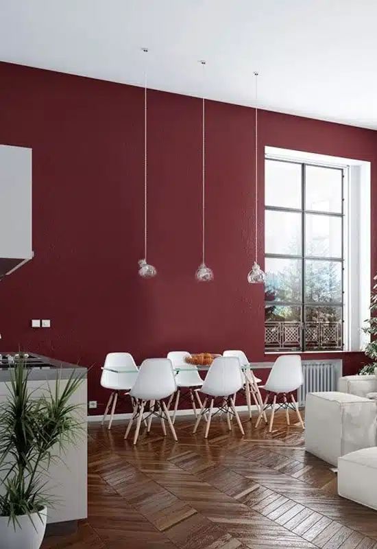  une cuisine blanche avec un mur bordeaux et du parquet chevron très moderne