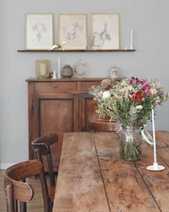 Une salle à manger vintage avec une table bois sur laquelle il y a un bouquet