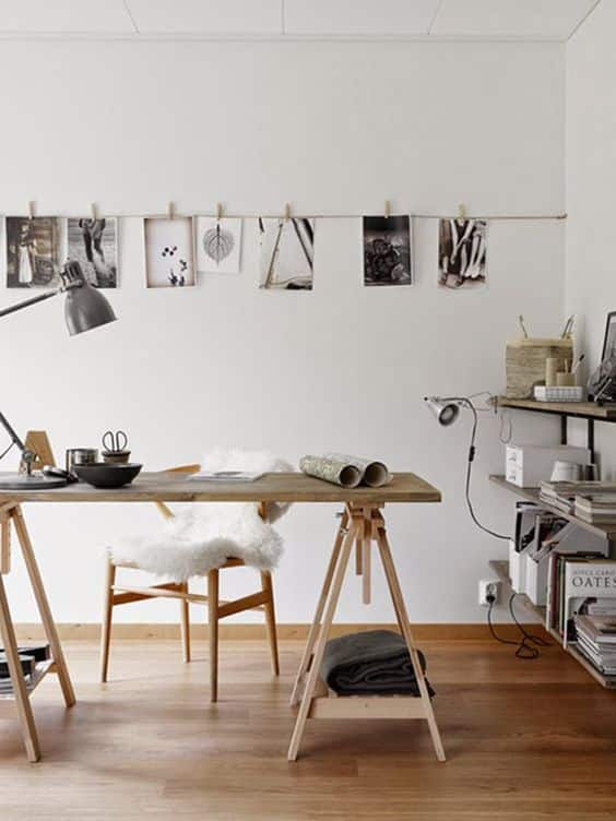 Un bureau scandinave avec meuble en bois, mur blanc et décoration avec des photos suspendues