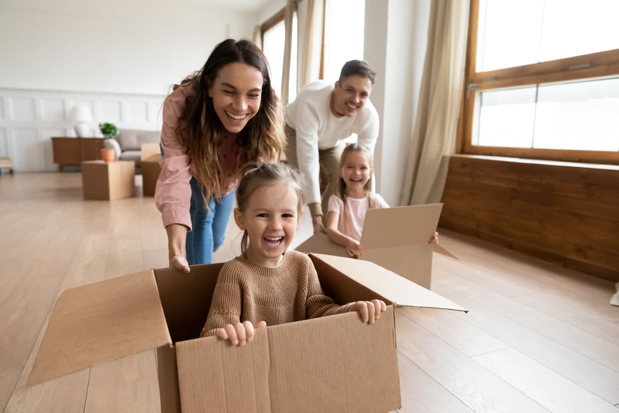 Parents heureux jouant leur enfant dans un carton de demenagement