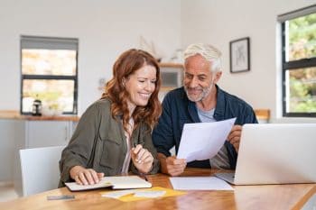 couple retraite qui regarde papier de travaux devant un ordinateur