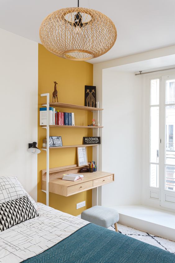 Un coin bureau sur mur jaune dans une petite chambre blanche