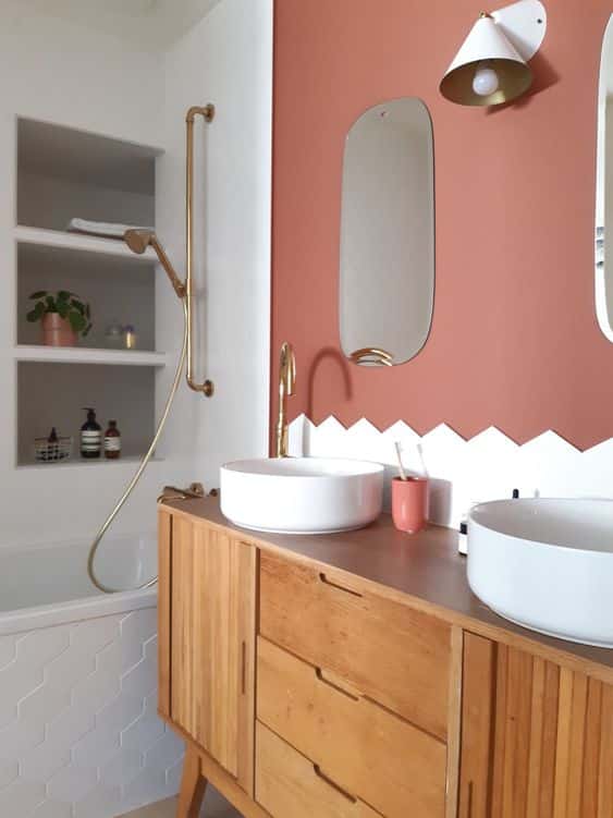 Une salle de bain avec baignoire et meuble vintage décorée par un mur terracotta