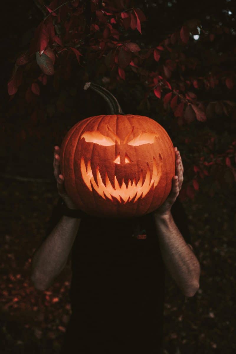 Homme tenant une lanterne faite avec une citrouille d'Halloween 