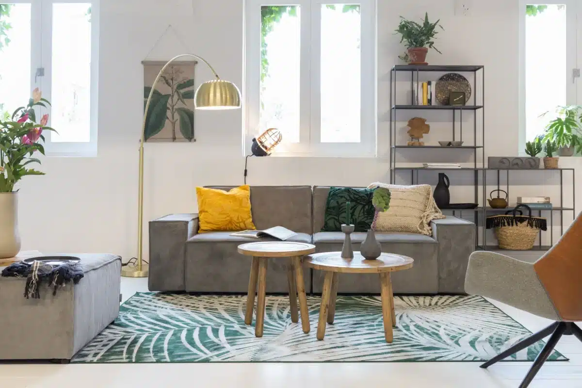 Un salon d'esprit tropical avec un canapé et un pouf en velours cotele gris