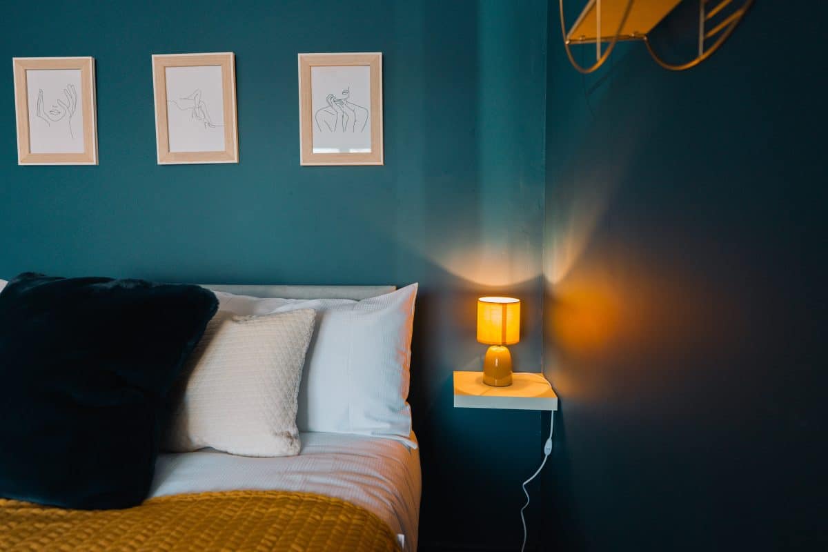 chambre avec peinture murale bleu canard et dessus de lit jaune moutarde
