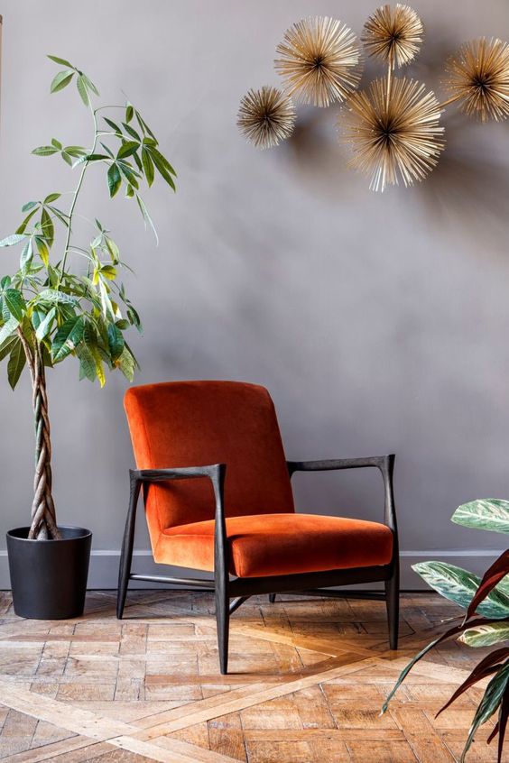 Un fauteuil vintage en velours côtelé terracotta a cote d'une plante 