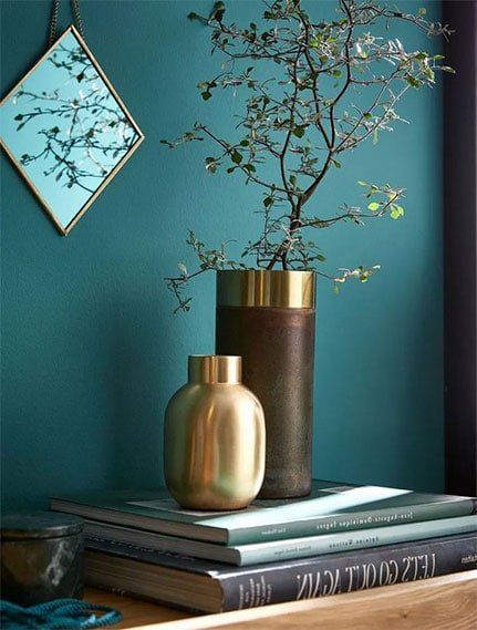 meuble decore avec des livre devant mur bleu canard avec miroirs
