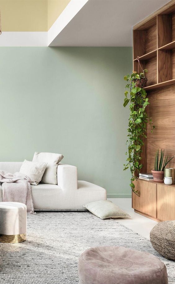 Un salon avec des pouf design et un mur vert celadon