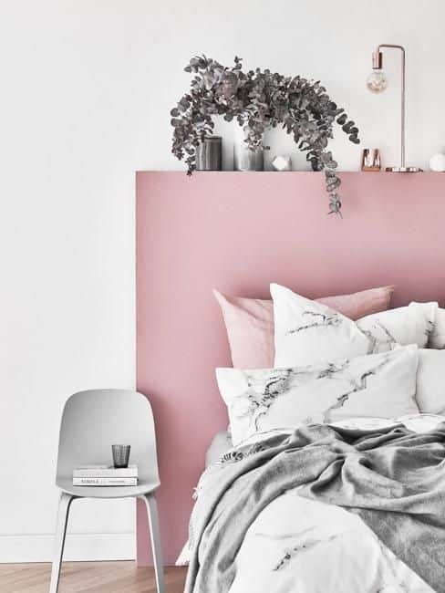 Une chambre blanche avec une tête de lit rose poudre
