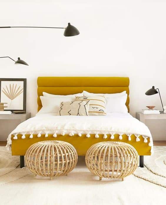 un lit avec une tete de lit et un cadre de lit jaune moutarde en tissu dans une chambre boheme