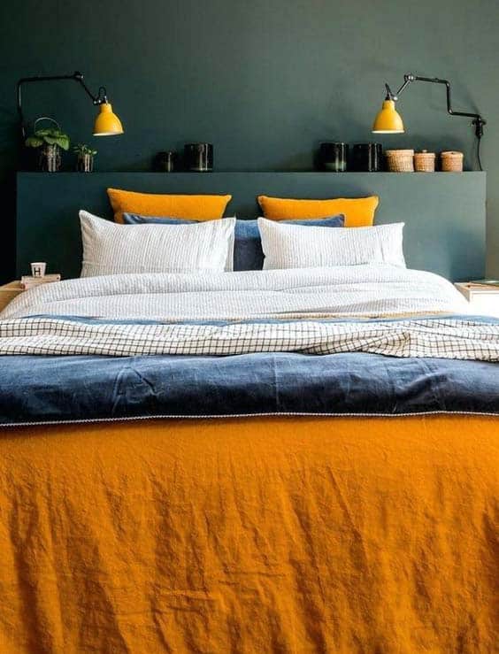 Un lit cosy avec un linge delit bleu et jaune moutarde