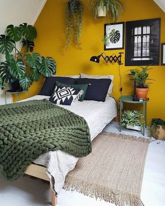 une chambre sous les combles avec un mur jaune moutarde et des plantes