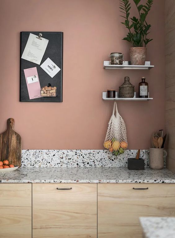 Une cuisine en bois avec un mur couvert d'une jolie couleur vieux rose