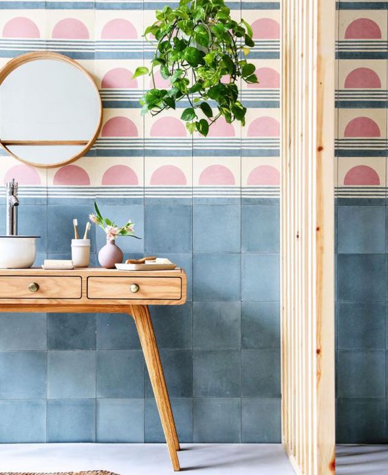 Une salle de bain rose et bleu avec un carrelage graphique et beaucoup de plante