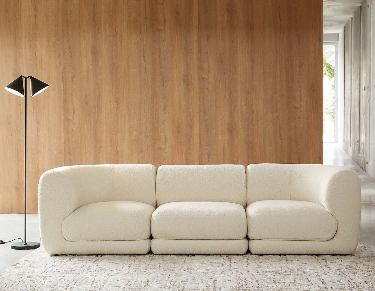 canapé modulable et arrondi blanc dans un salon avec des murs en bois