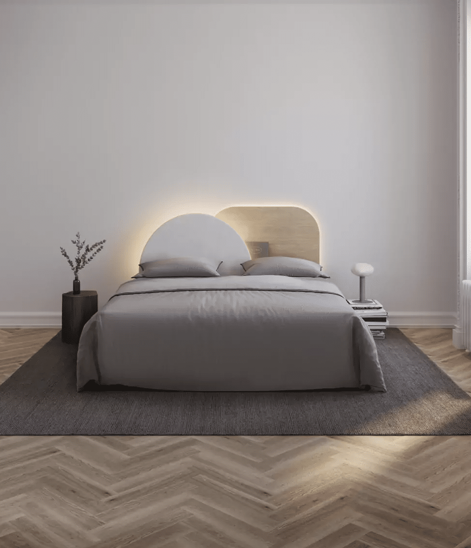 Une chambre blanche avec parquet chevron et tête de lit asymétrique avec des rangements 