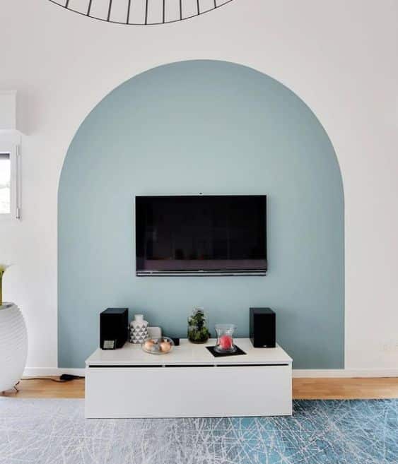 Un salon aux murs blanc avec une arche en peinture bleu qui marque le coin tele