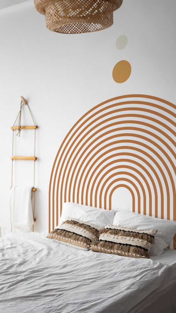 Une chambre blanche et matière naturelle avec une tete de lit en arc en ciel peint sur le mur