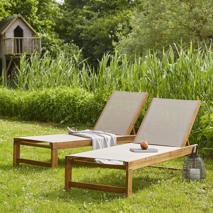 deux chaises longues en bois avec toile beige sur un pelouse verdoyante