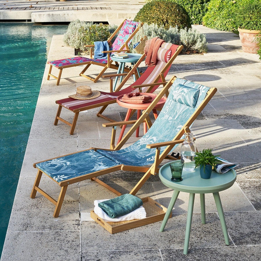 Trois chaises longues alignées les unes derriere les autres au bord d'une piscine