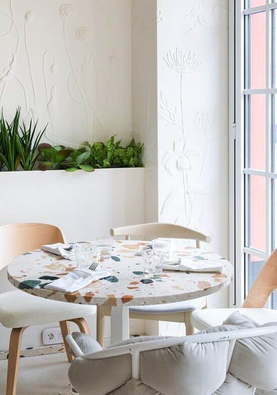 Une salle a manger cosy à la déco blanche avec une table en terrazzo