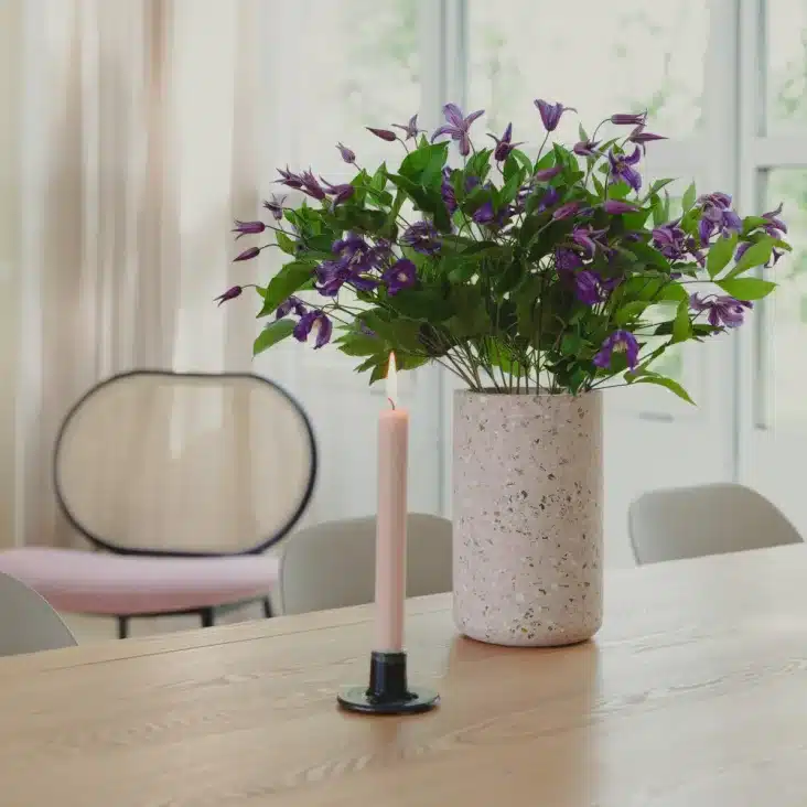 vase en terrazzo avec bouquet de fleur violette sur une table en bois 