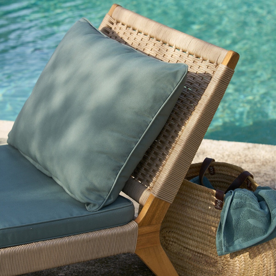 Zoom sur une chaise longue avec matela et coussin bleu près d'une piscine