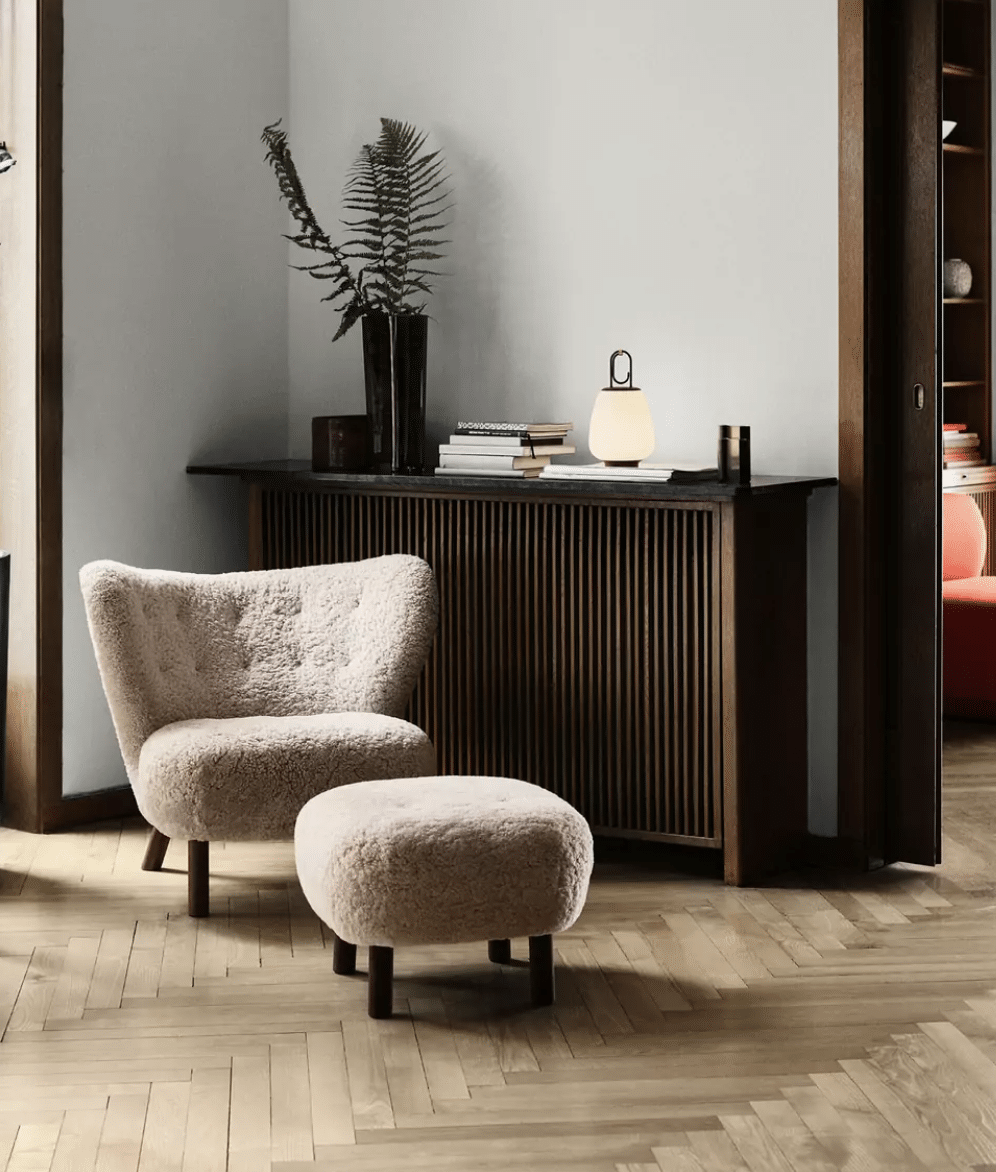 un salon avec meuble en bosi sombre et fauteuil bouclette blanc 