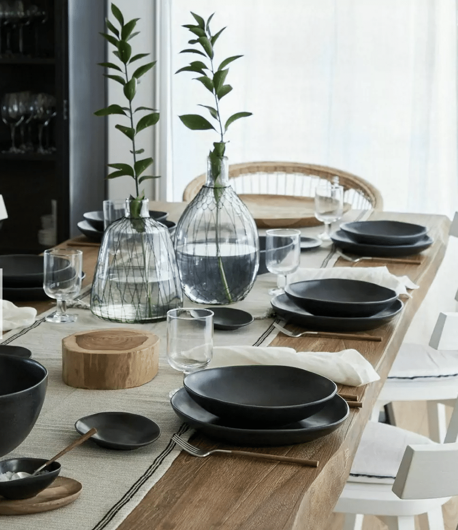 table en bois avec vaisselle noire et centre de table en lin