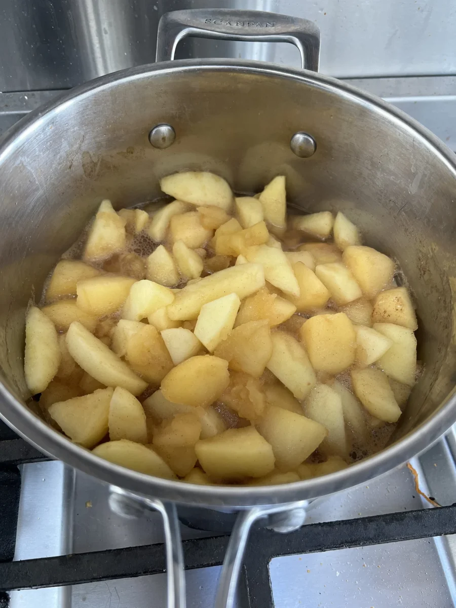 Casserole en inox contenant des pommes en compote sur le feu