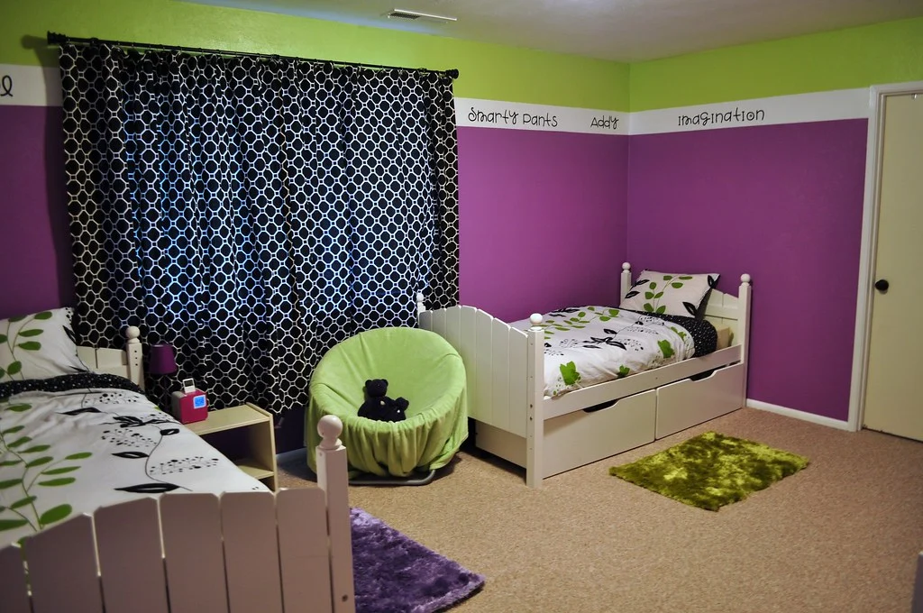 Chambre partagée avec deux lits simples, murs violets et bandeau vert anis