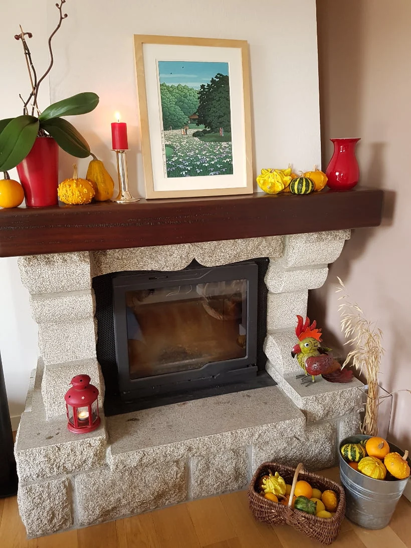 Cheminée en granit avec un manteau en bois décoré de coloquintes et de fleurs d’automne