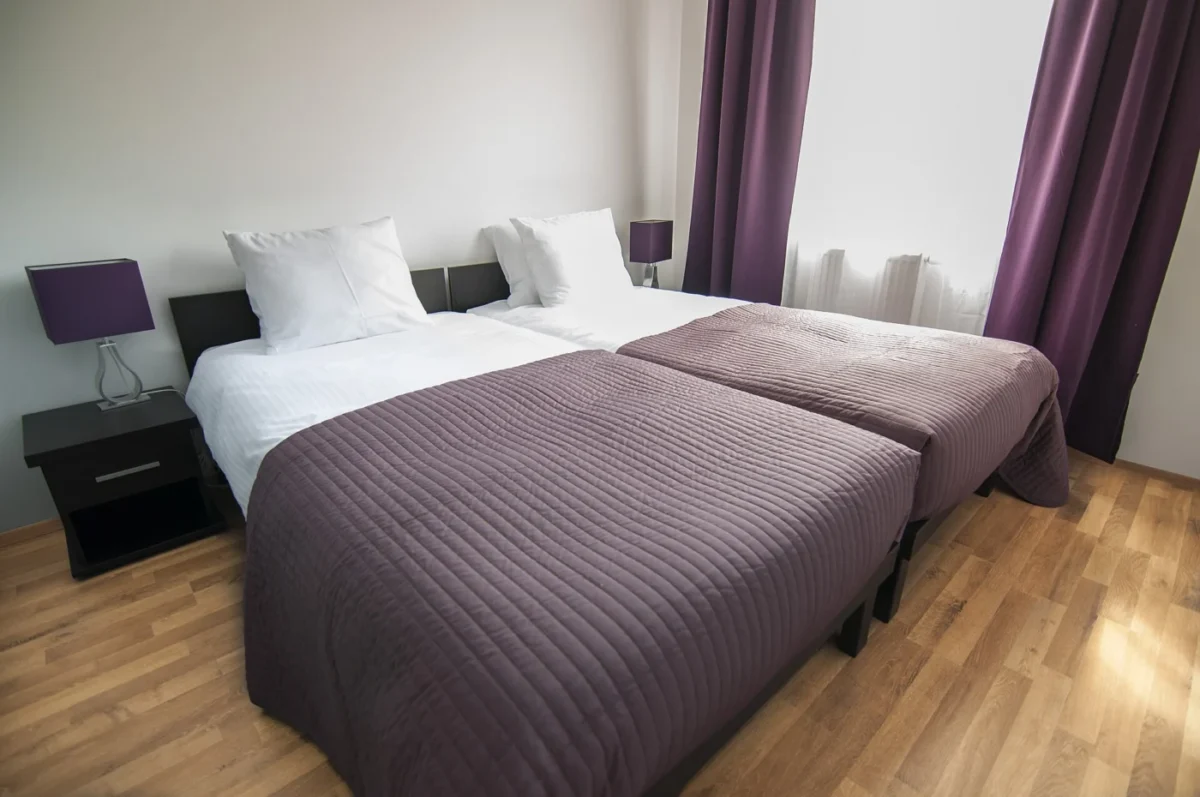Deux lits simples côte à côte avec chevets et lampes assortis