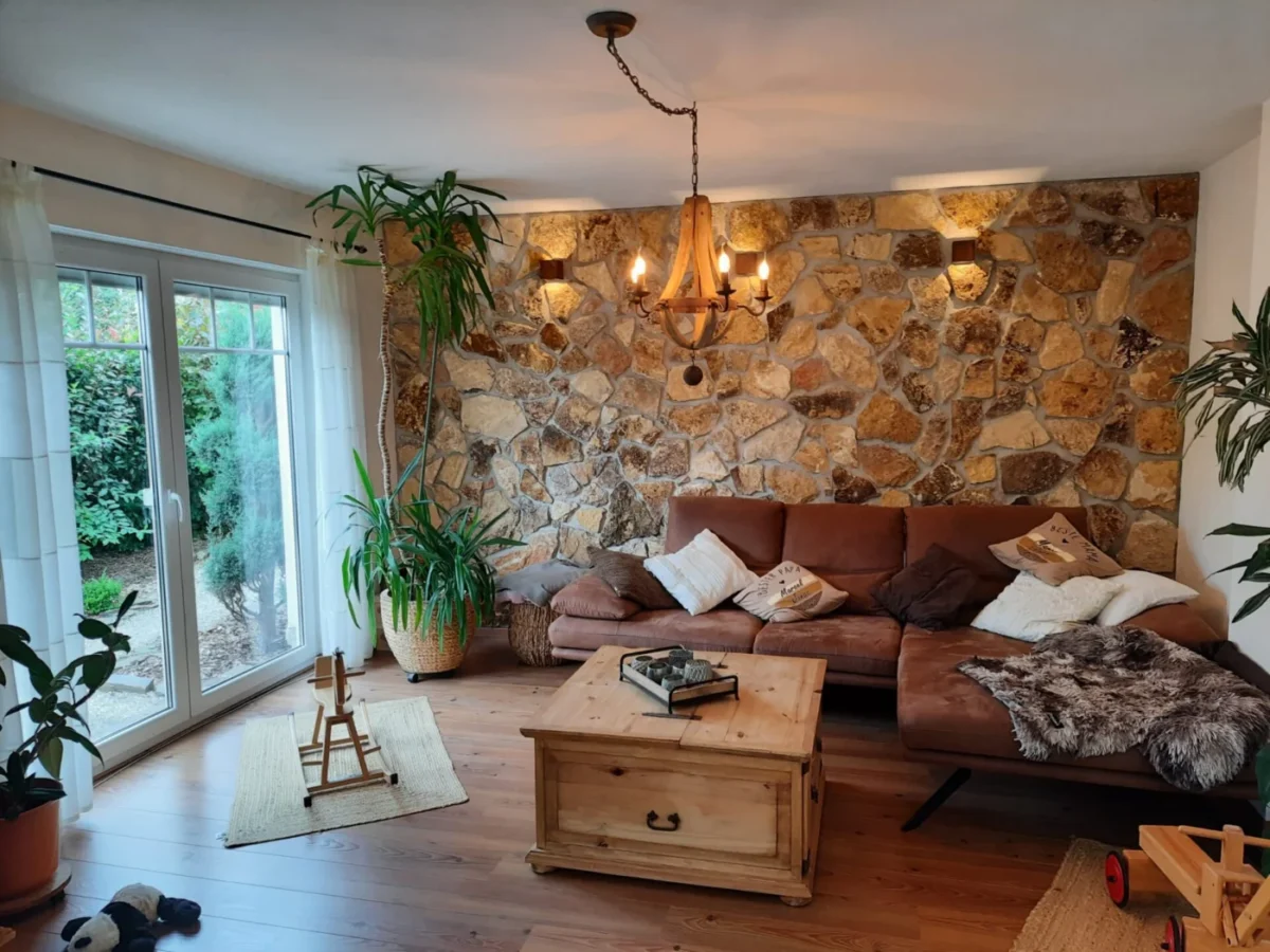 Salon avec un mur d’accent en parement de pierre naturelle derrière un canapé en cuir
